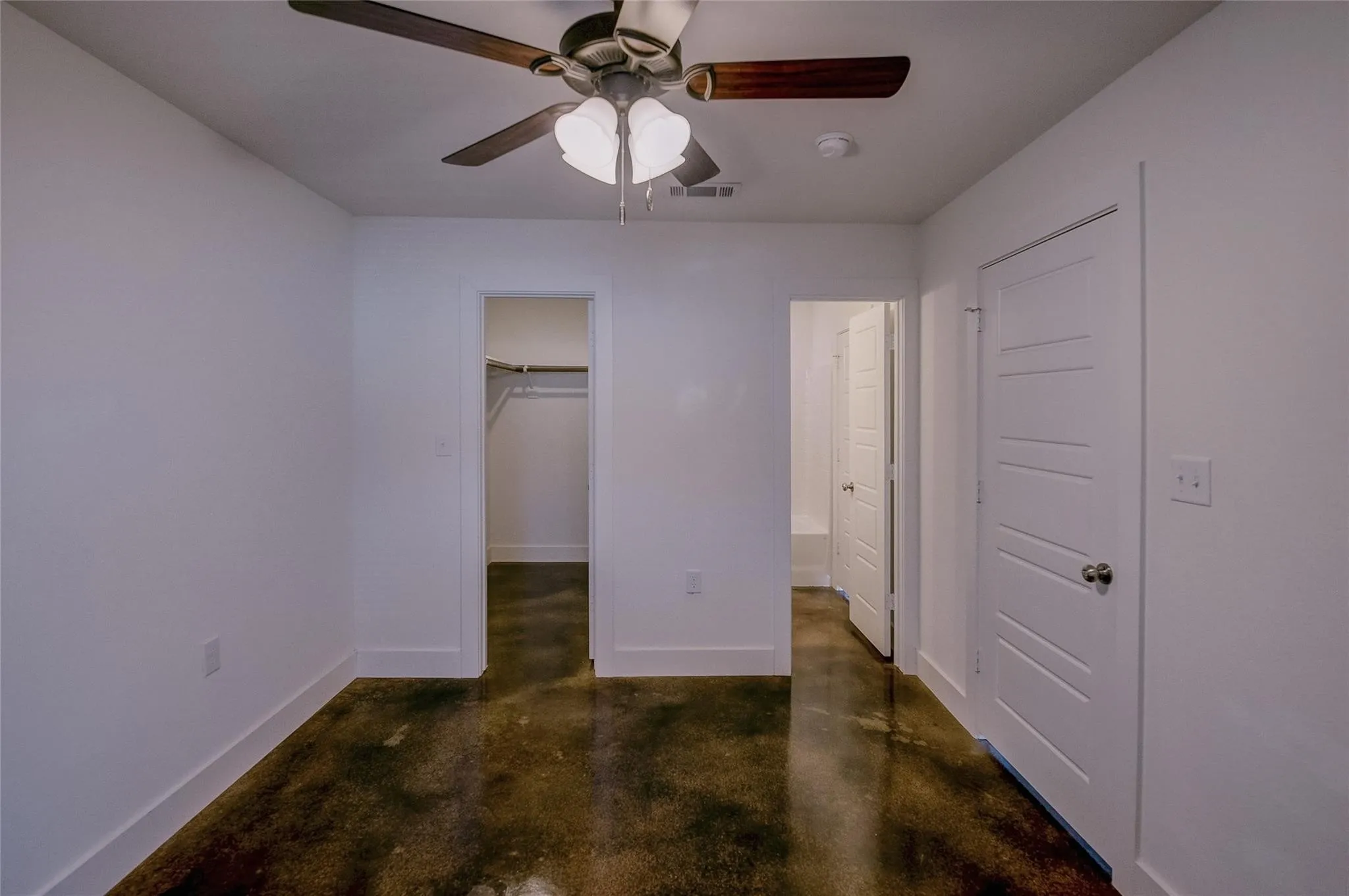 Bedroom with hard surface floors, ceiling fan and bathroom