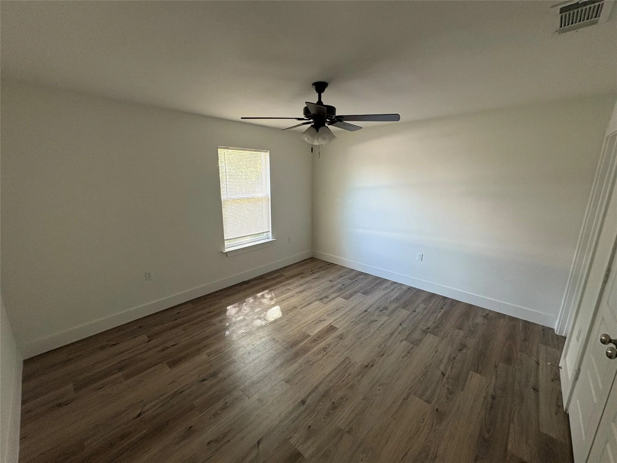 Bedroom with hard surface floors, ceiling fan and bathroom
