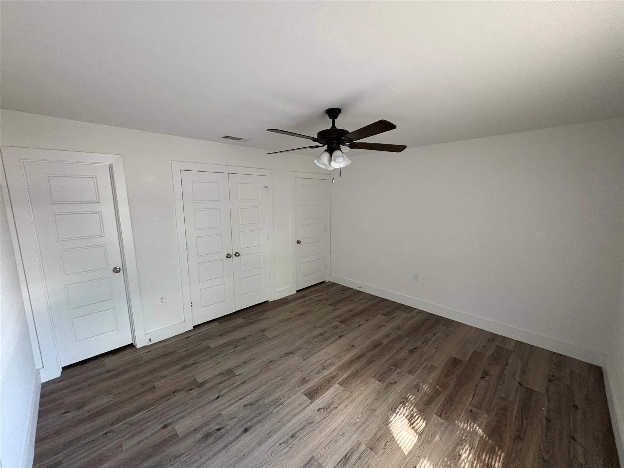 Bedroom with hard surface floors, ceiling fan and bathroom