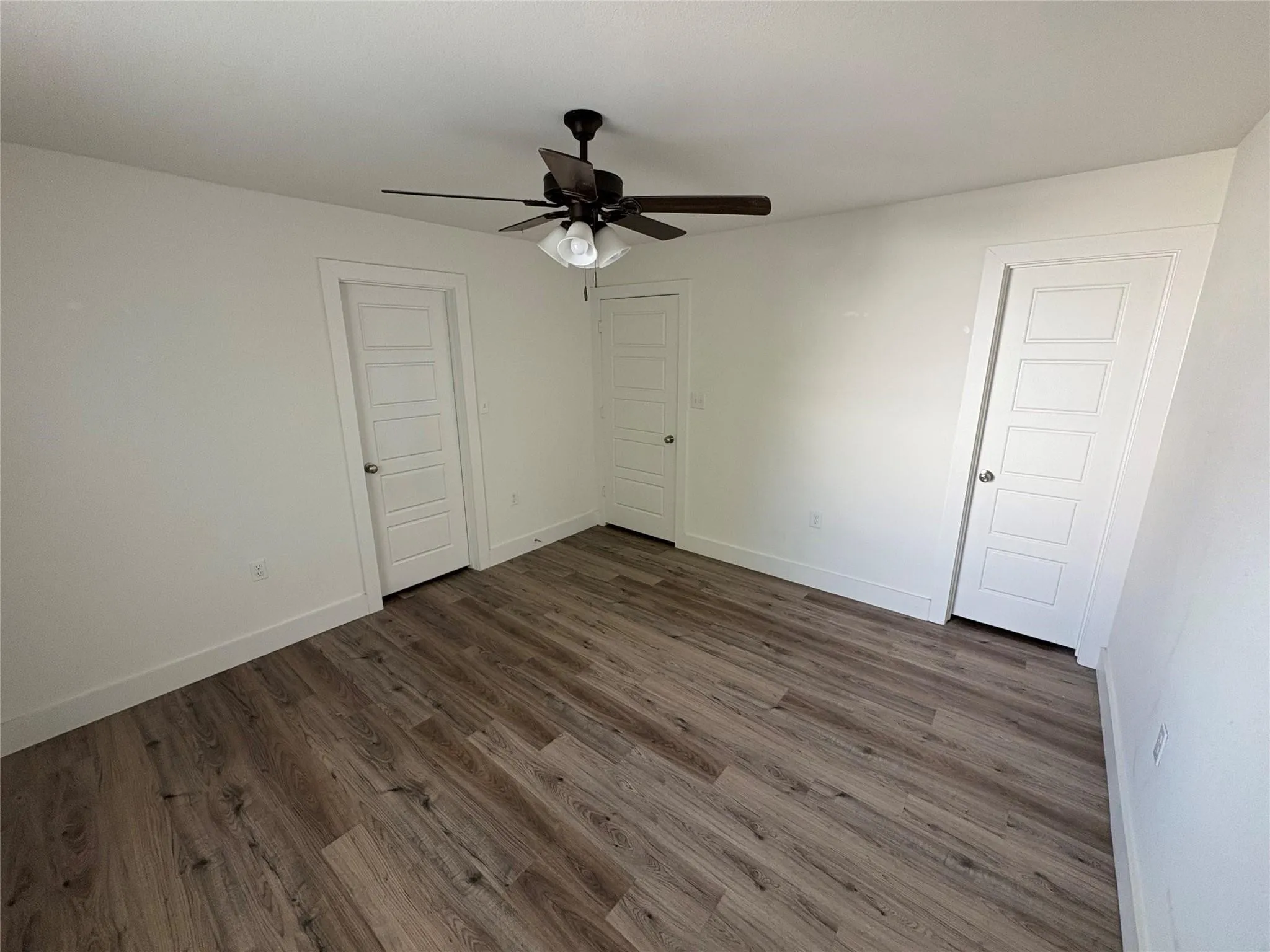 Bedroom with hard surface floors, ceiling fan and bathroom