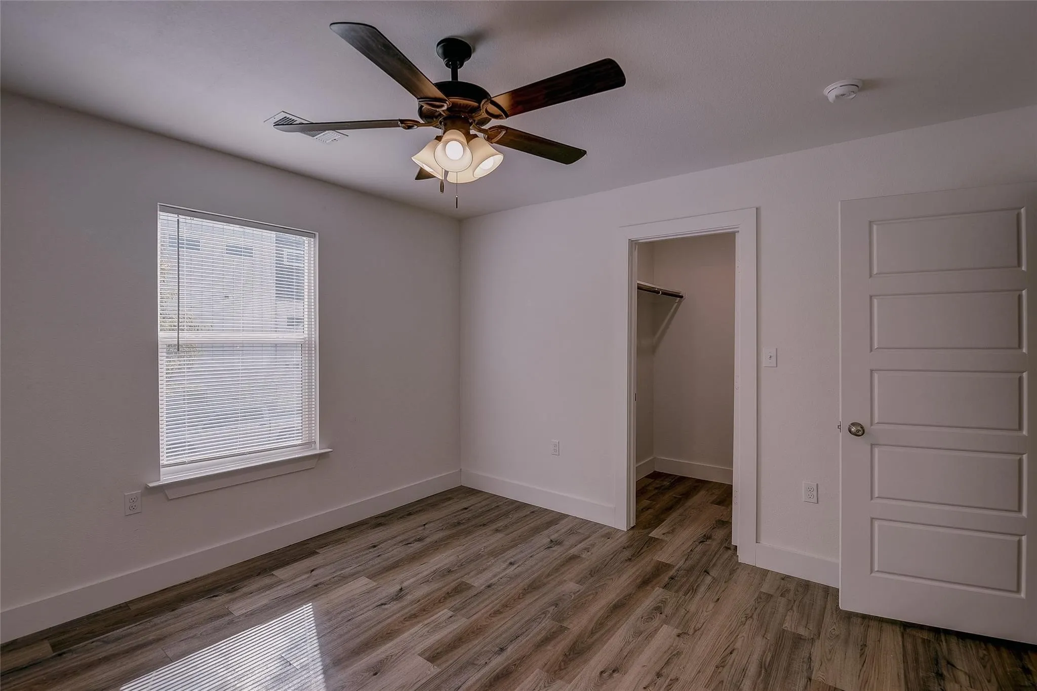 Bedroom with hard surface floors, ceiling fan and bathroom