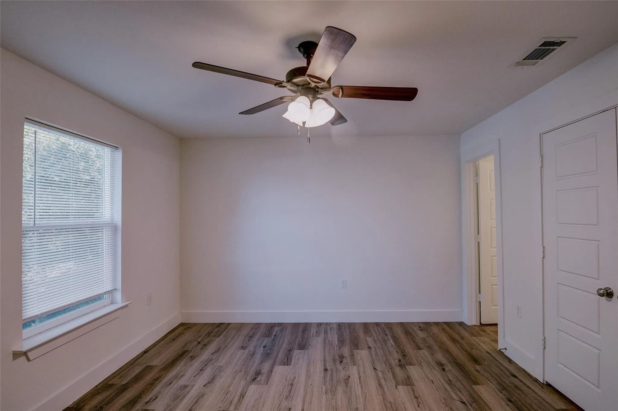 Bedroom with hard surface floors, ceiling fan and bathroom