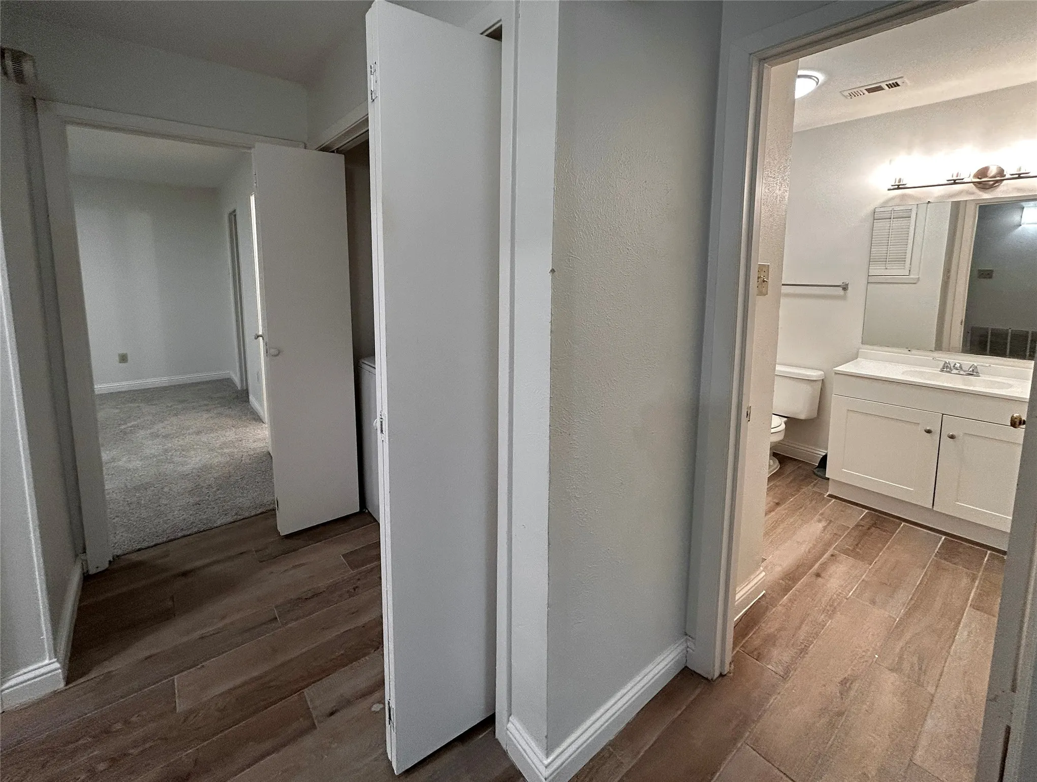 The laundry room has folding doors and is located in the hallway beside the secondary bathroom.