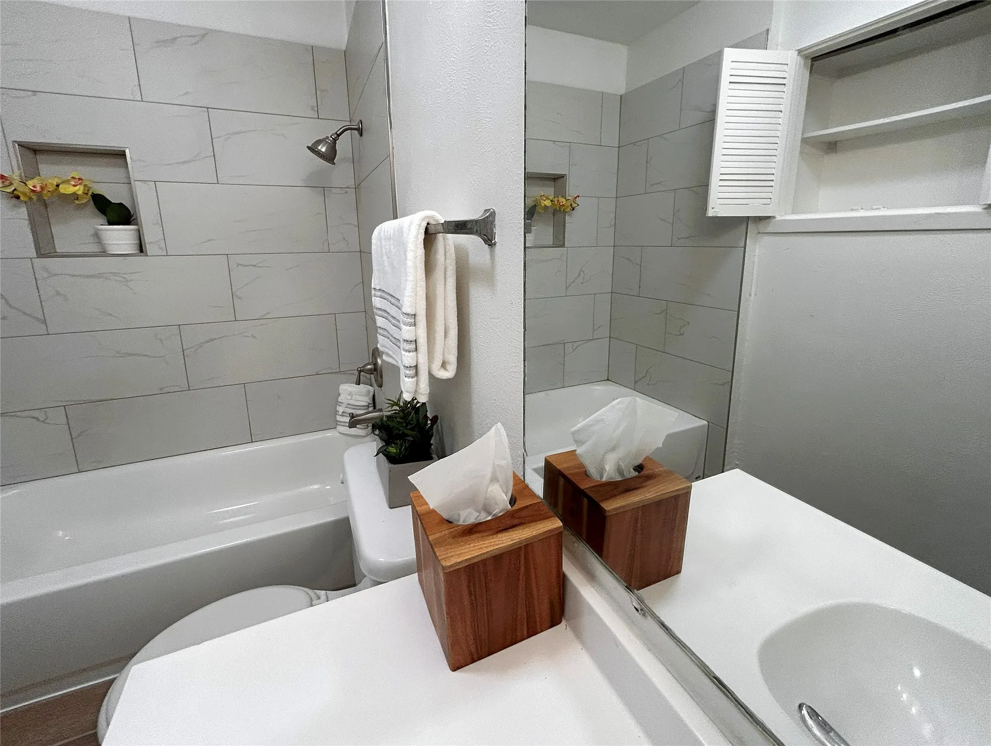 The secondary bath has a shower/bath combo, a white vanity and a cute towel closet with louvered doors.