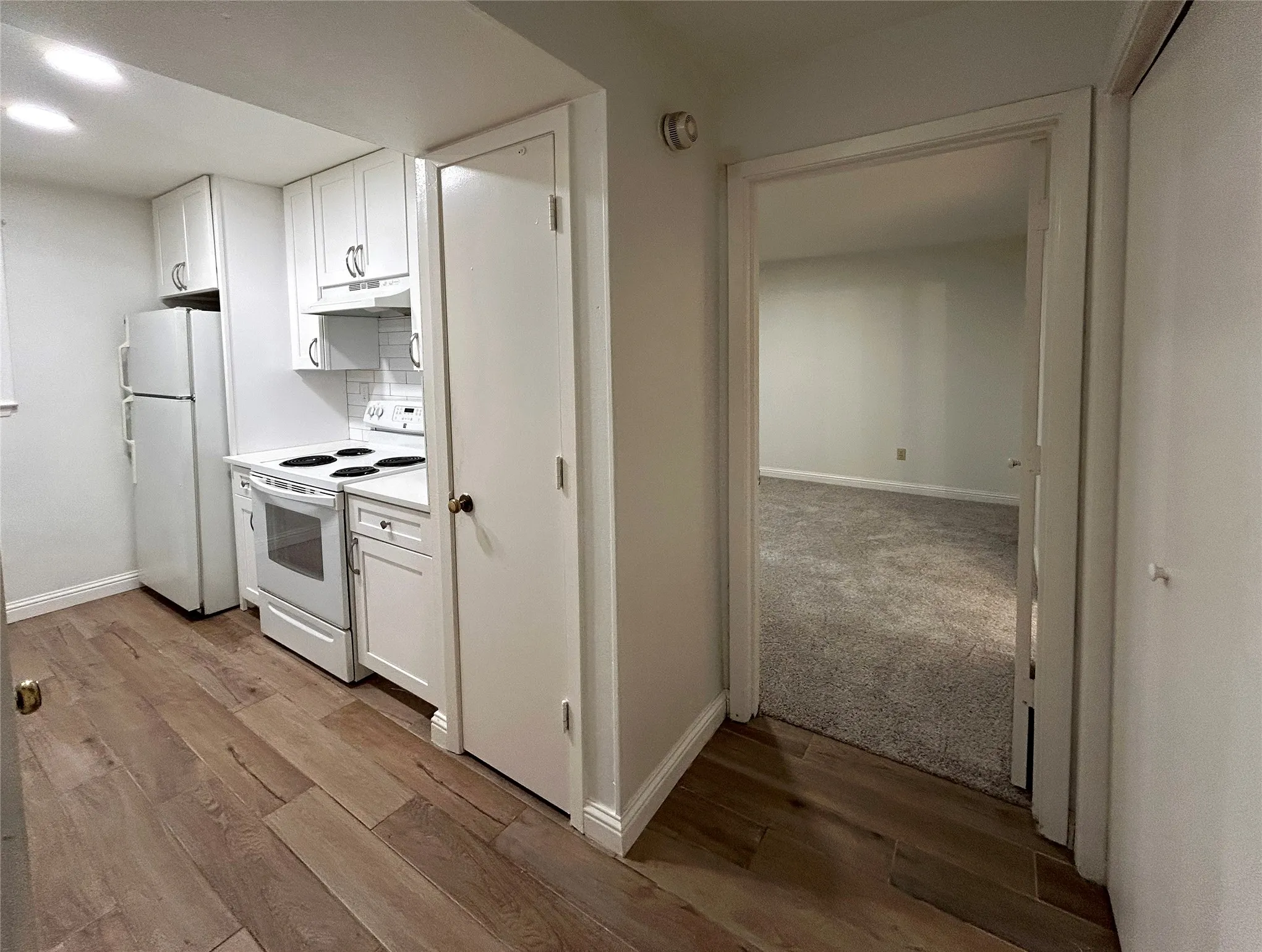 The kitchen has a convenient pantry, white appliances, white cabinetry, designer cabinets and subway tile backsplash. The laundry room is across the hallway from the kitchen next to the primary bedroom.