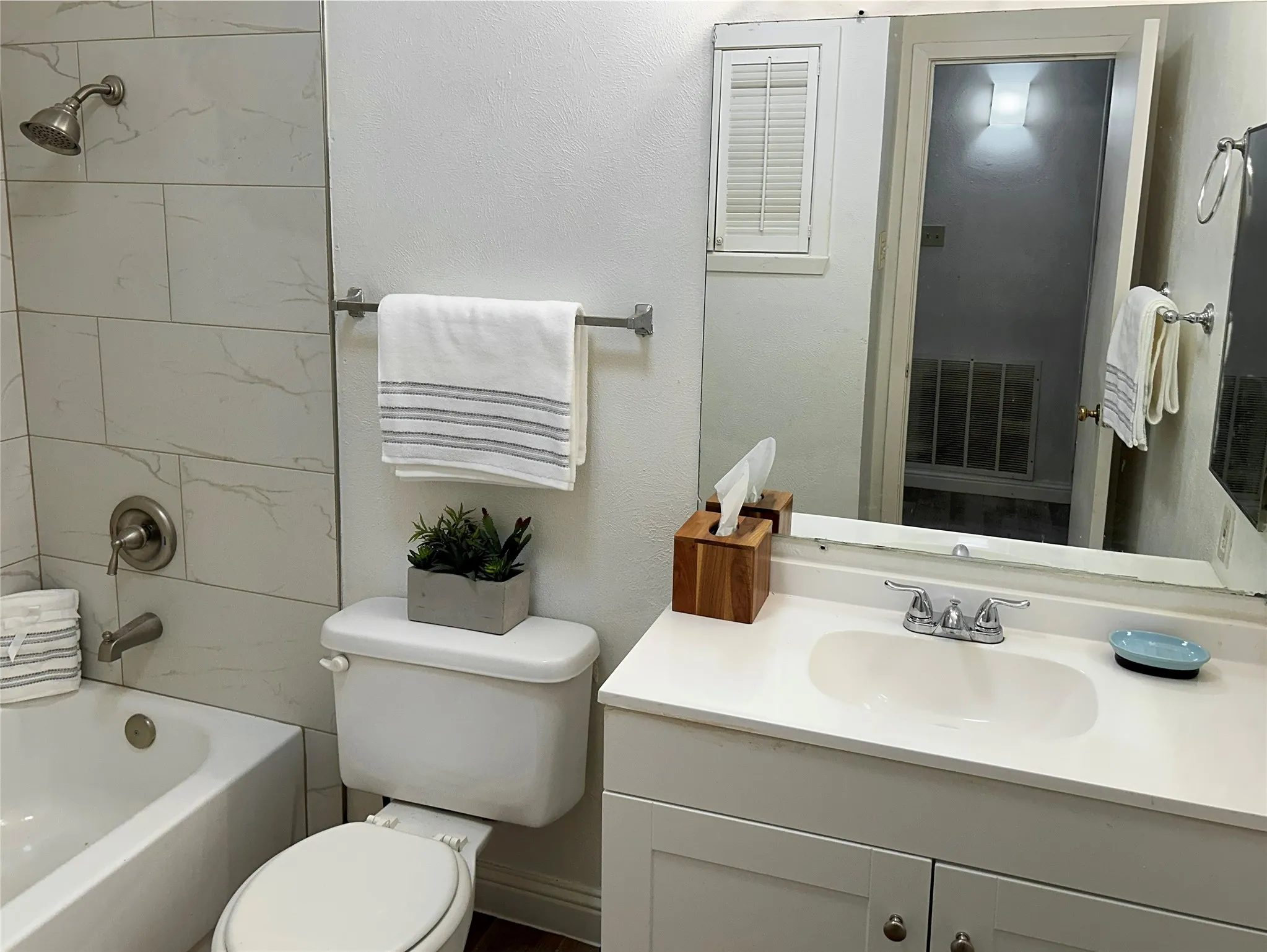 The secondary bath has a shower/bath combo, a white vanity and a cute towel closet with louvered doors.