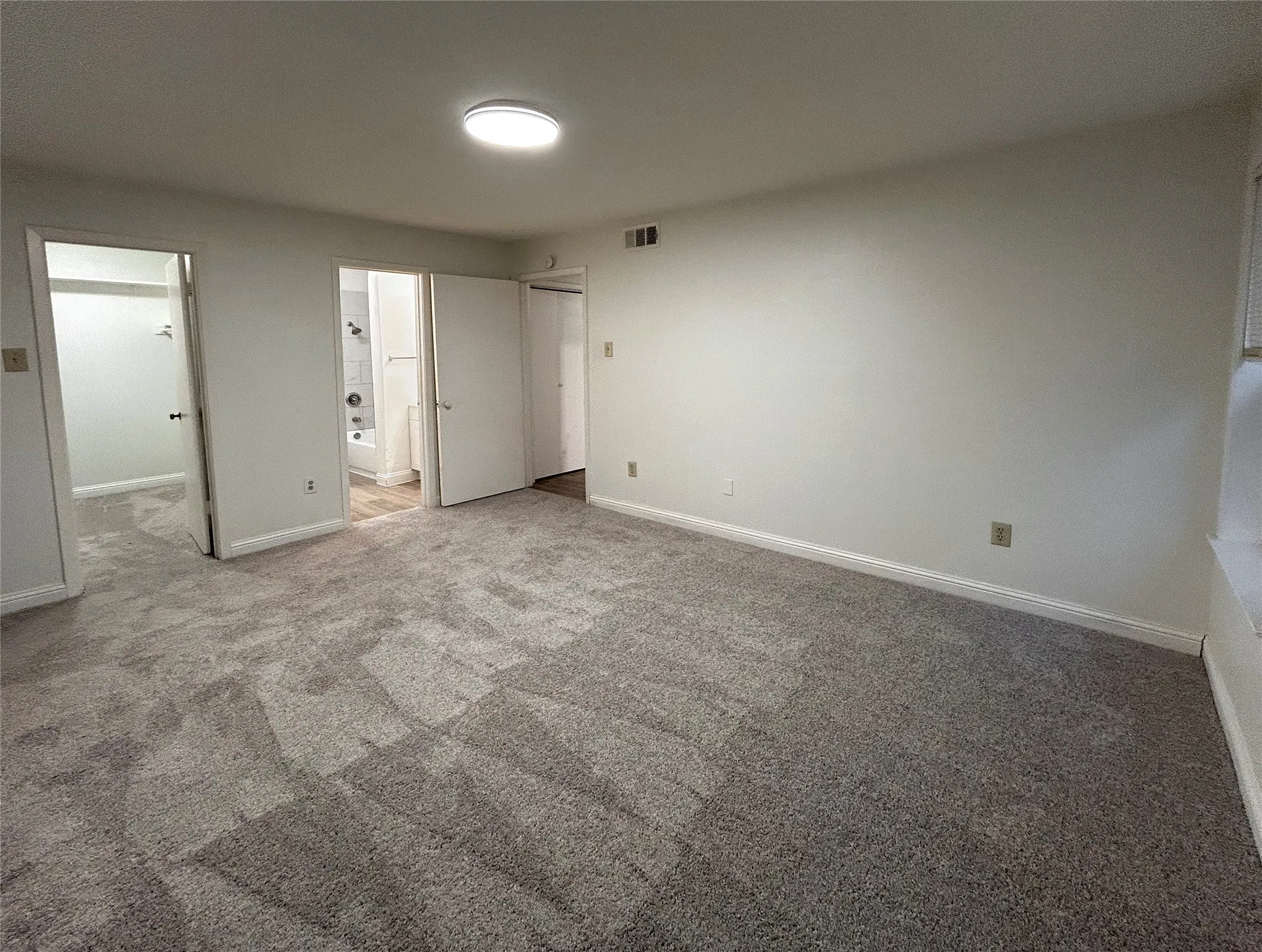 The primary bedroom has an ensuite bathroom and a walk-in closet. It is located at the end of the hallway near the laundry room. New carpet was installed in 2026.
