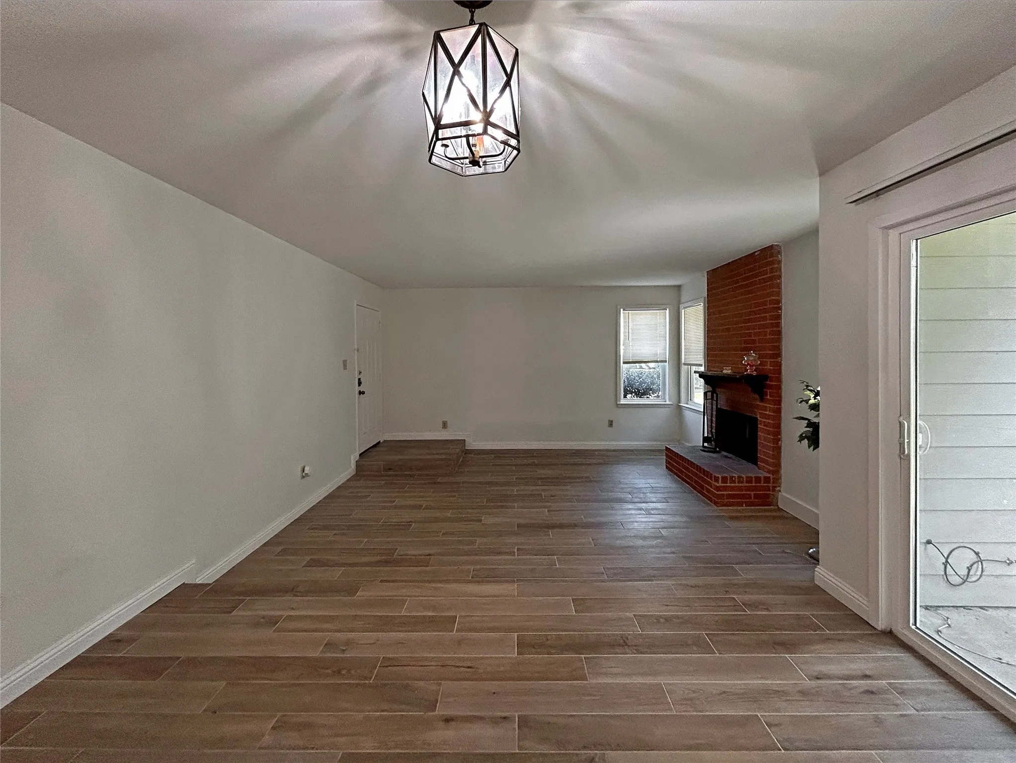 The sunken living room features ceramic tile flooring. The dining area has a chandelier, a sliding glass door to the patio and a breakfast bar to the kitchen.