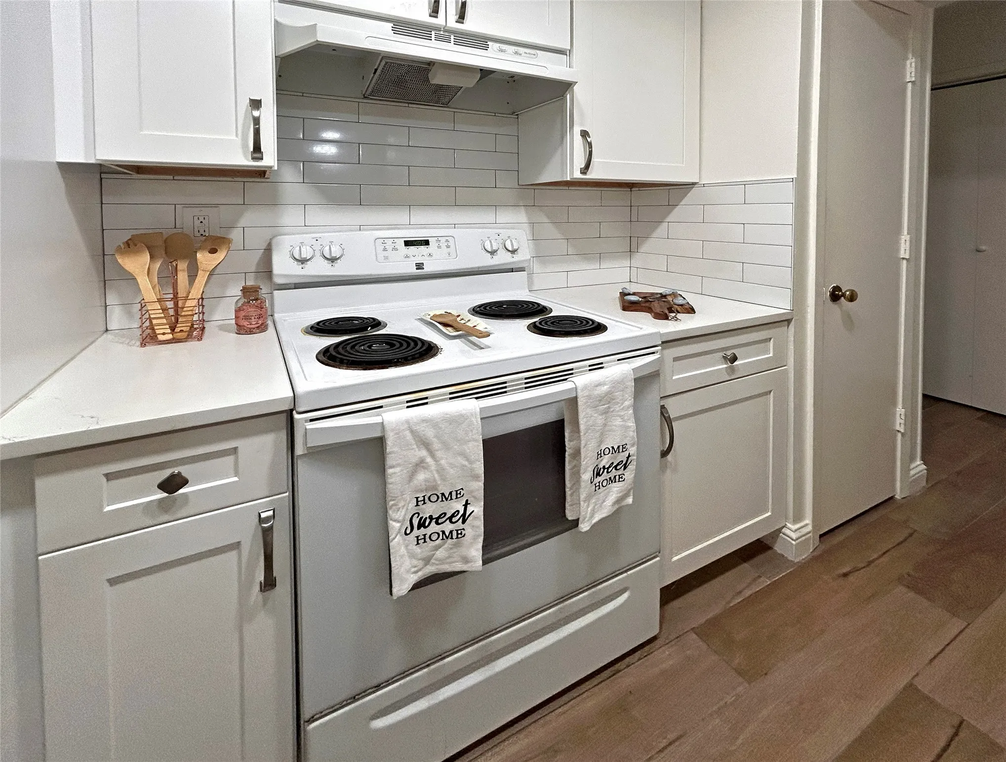 The kitchen has a convenient pantry, white appliances, white cabinetry, designer cabinets and subway tile backsplash.
