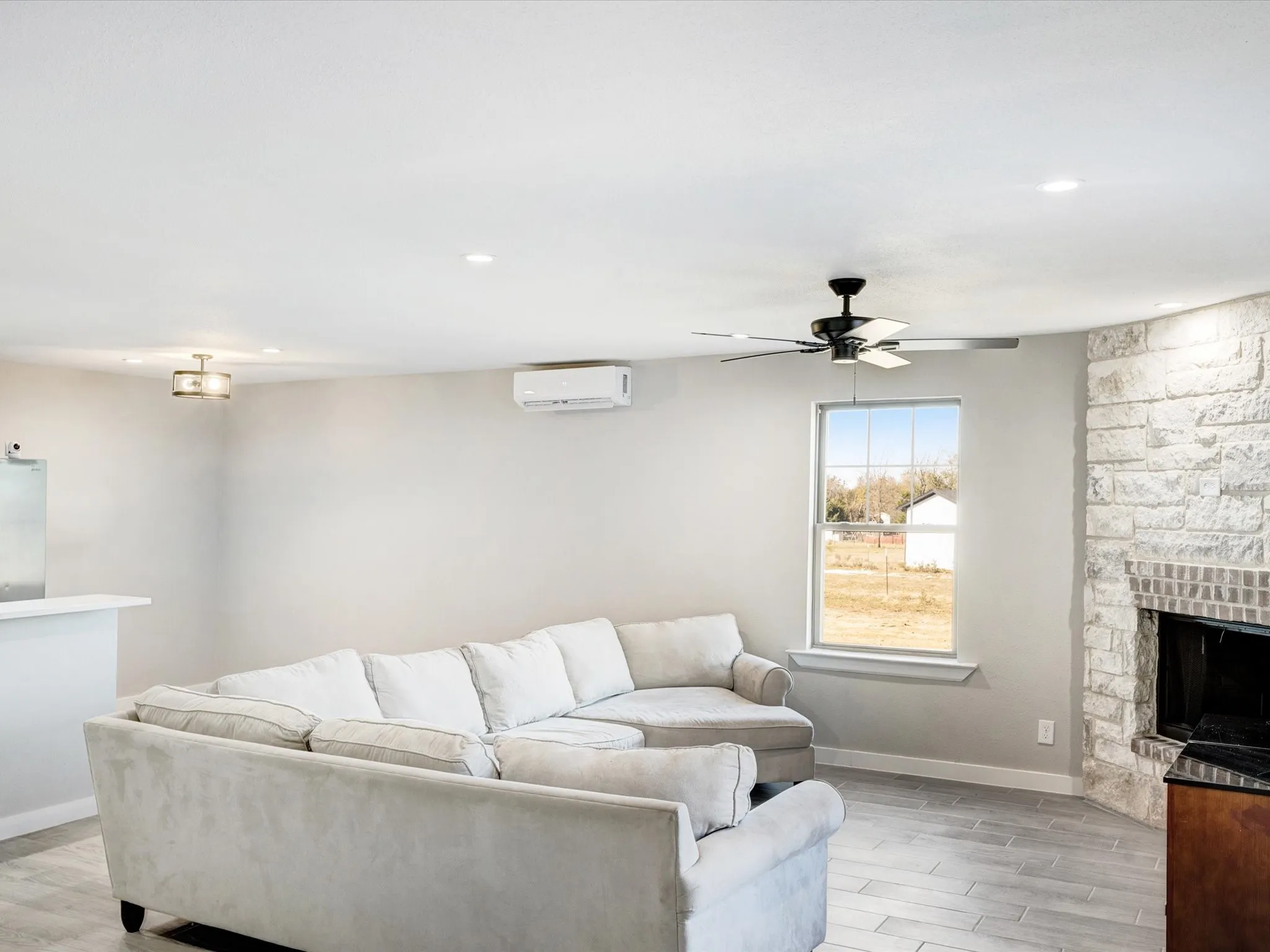 Living area with wood finish floors, ceiling fan, a fireplace, and recessed lighting