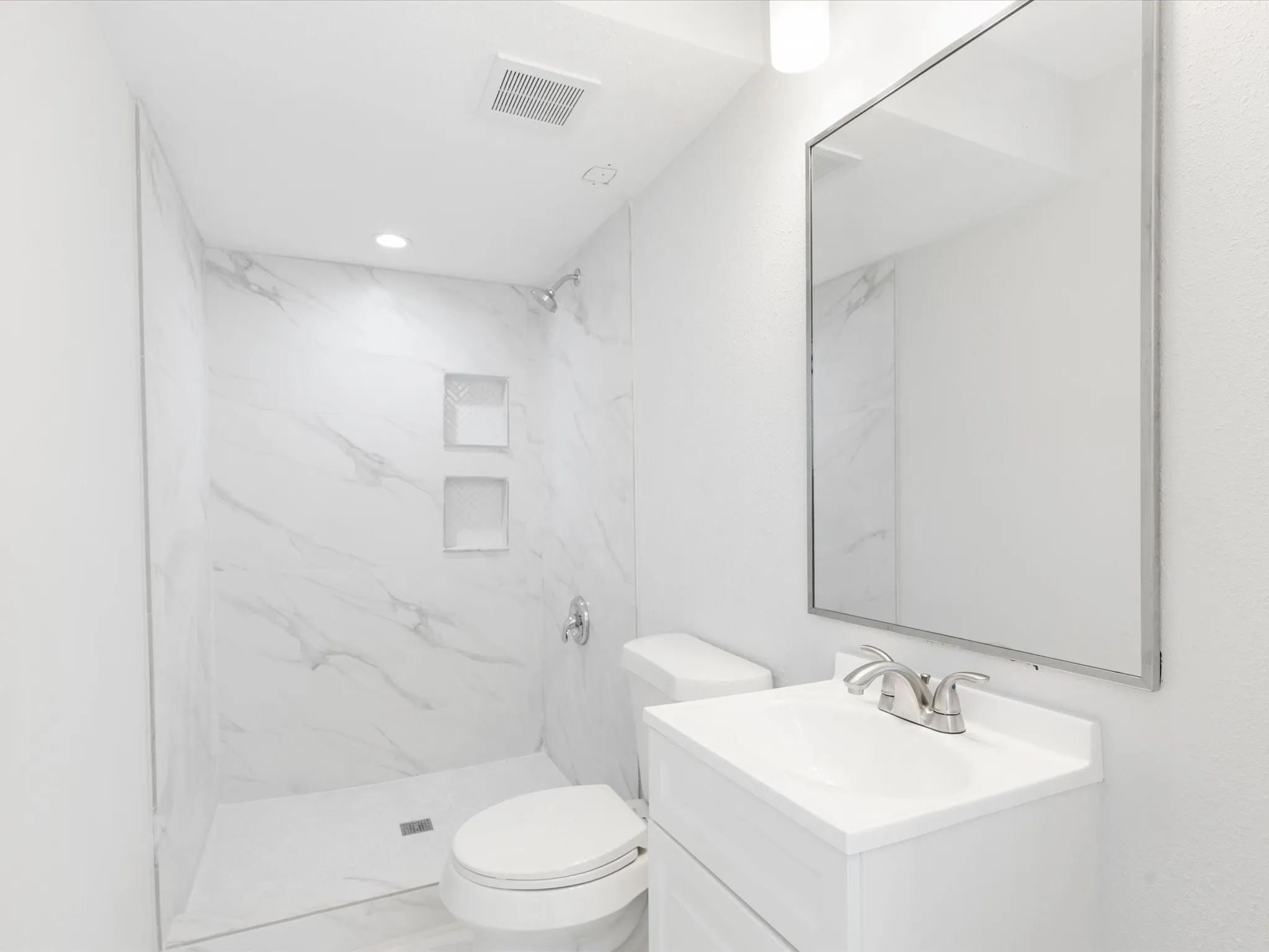 Bathroom with vanity and a marble finish shower