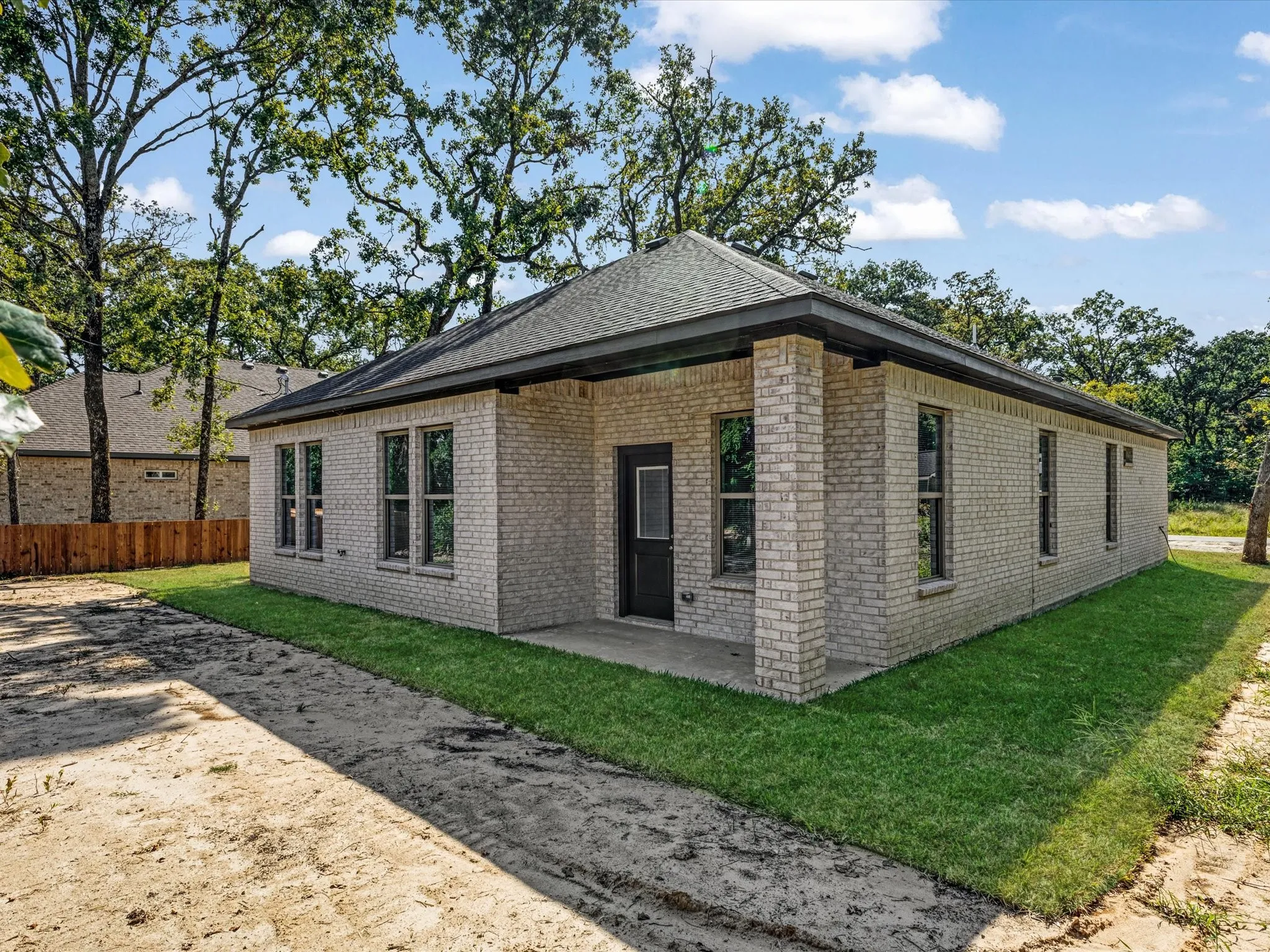 View of home's exterior featuring brick siding, a patio, and a shingled roof