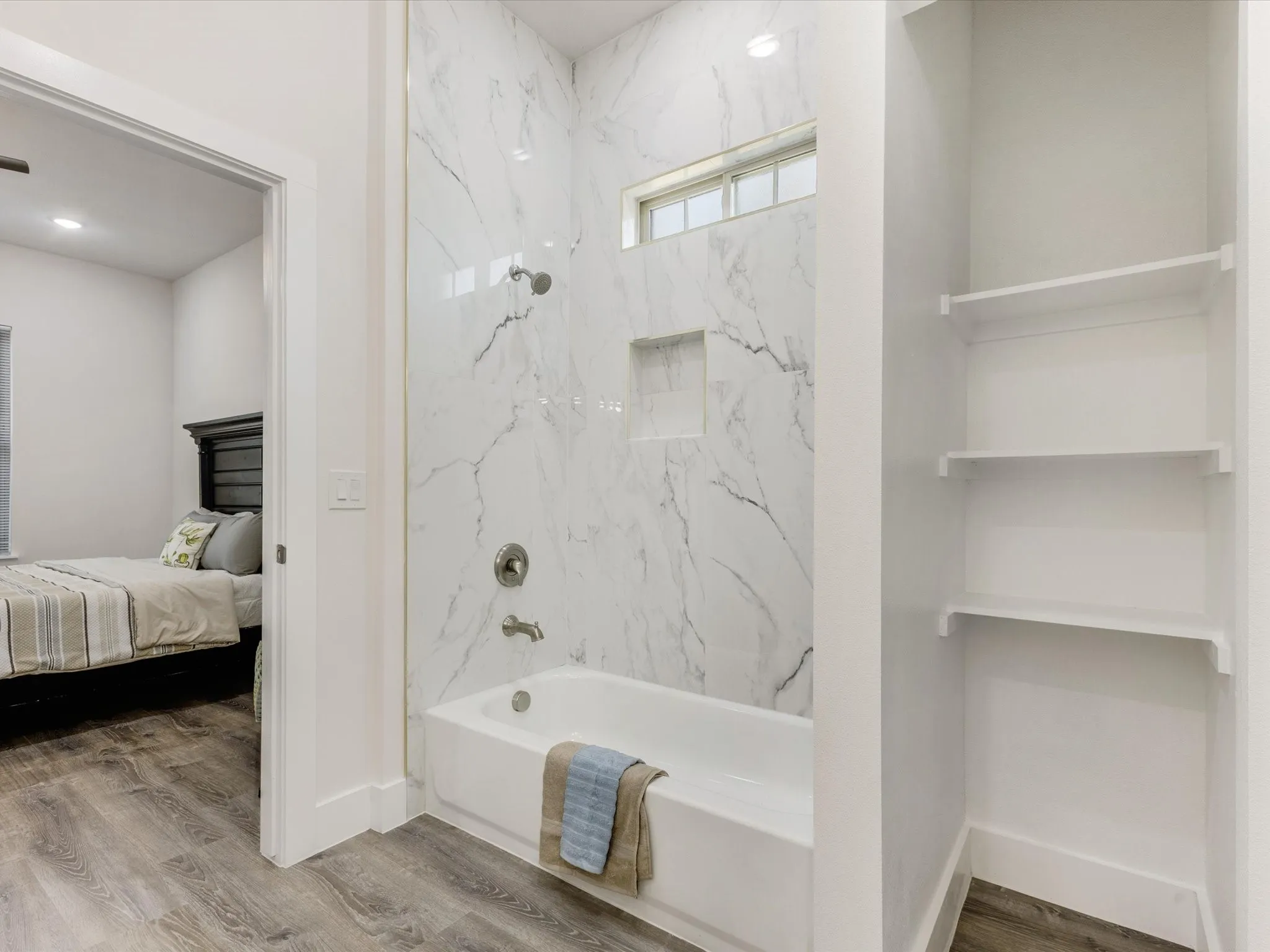 Bathroom featuring wood finished floors, bathing tub / shower combination, and ensuite bathroom