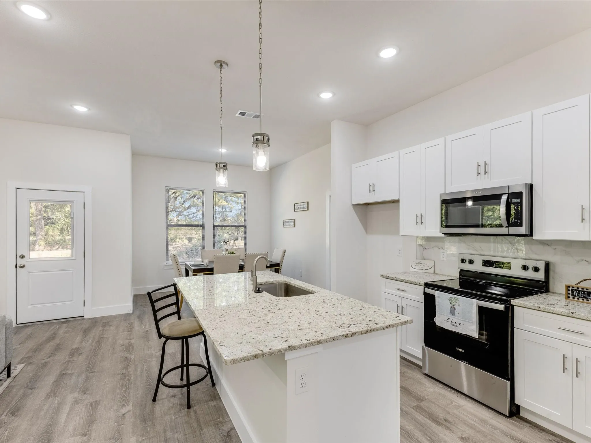 Kitchen with stainless steel appliances, a kitchen bar, white cabinets, and backsplash