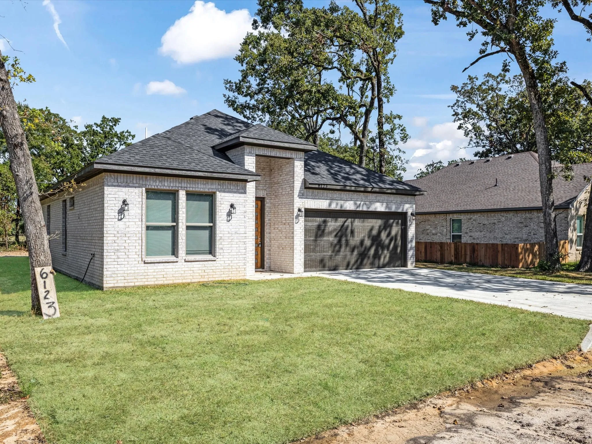 View of front of house with a shingled roof, brick siding, driveway, and an attached garage
