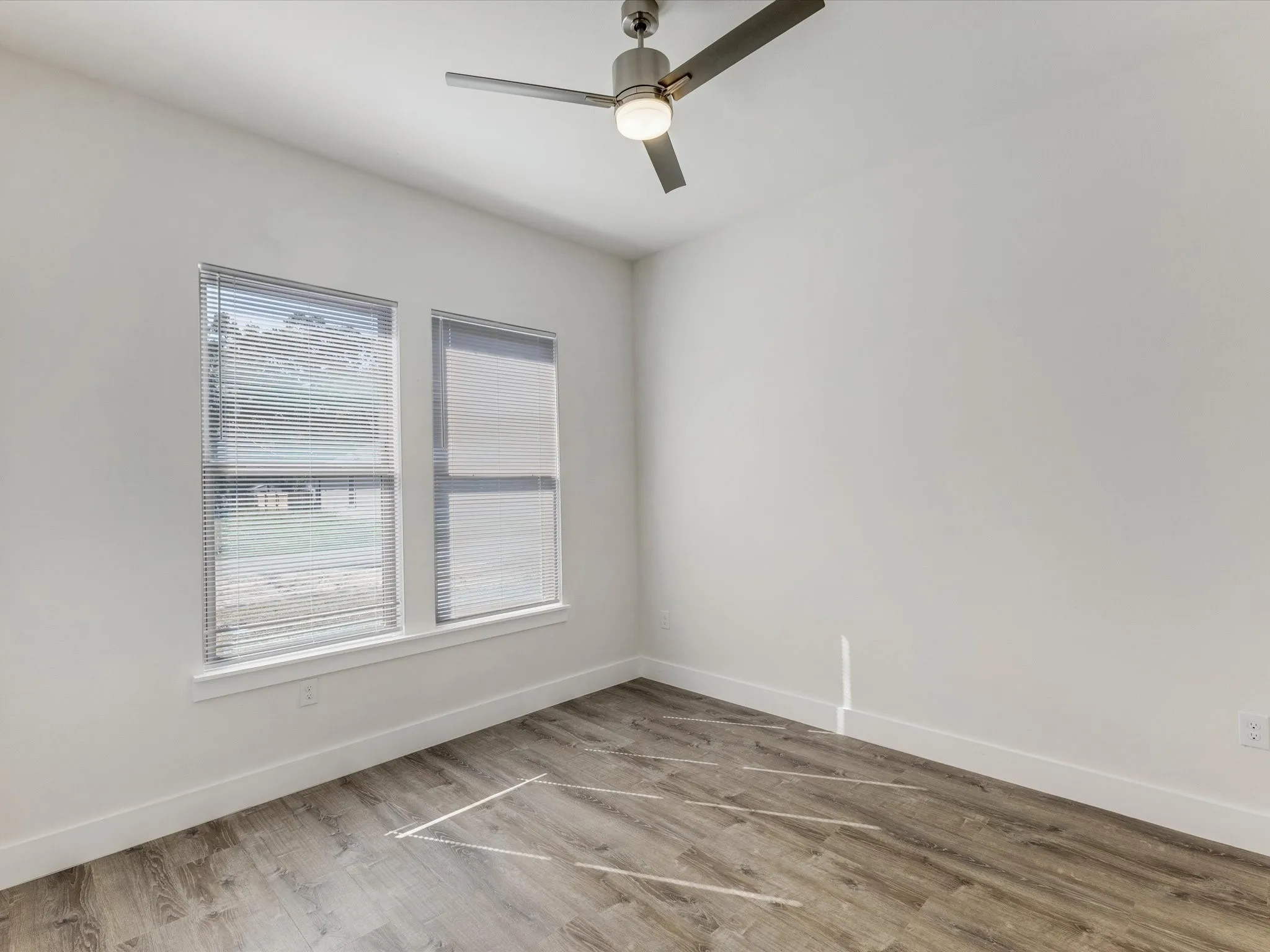 Empty room featuring light wood finished floors and ceiling fan
