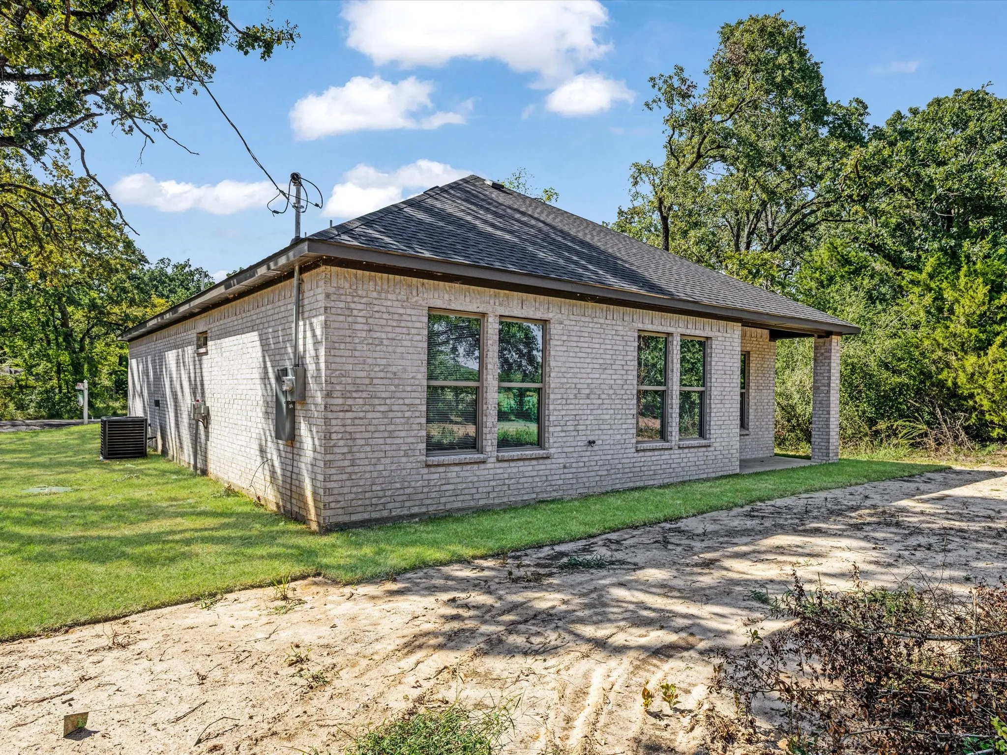 View of home's exterior with brick siding, a patio area, and a yard
