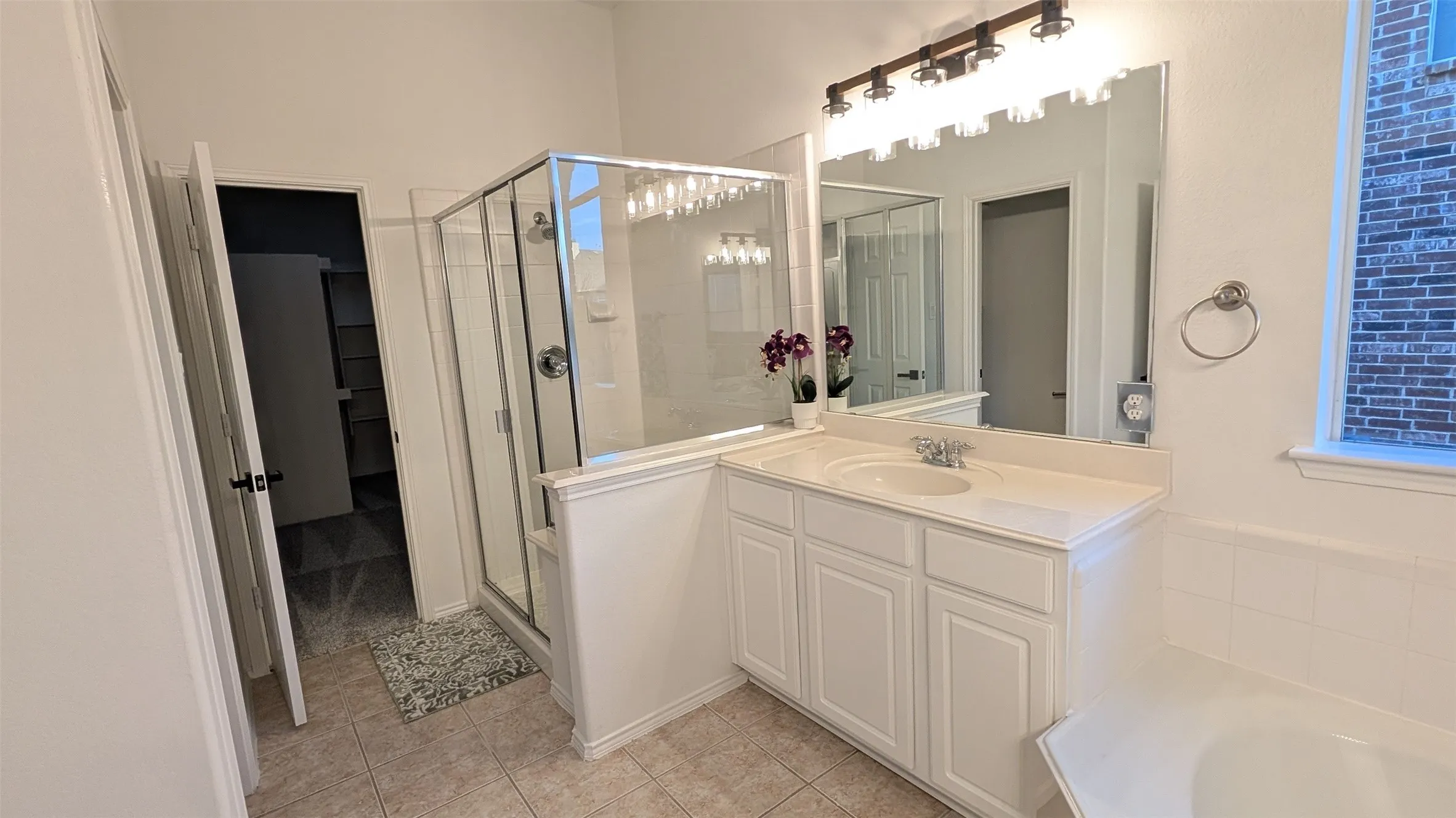 Full bathroom featuring a shower stall, a garden tub, vanity, and light tile patterned floors