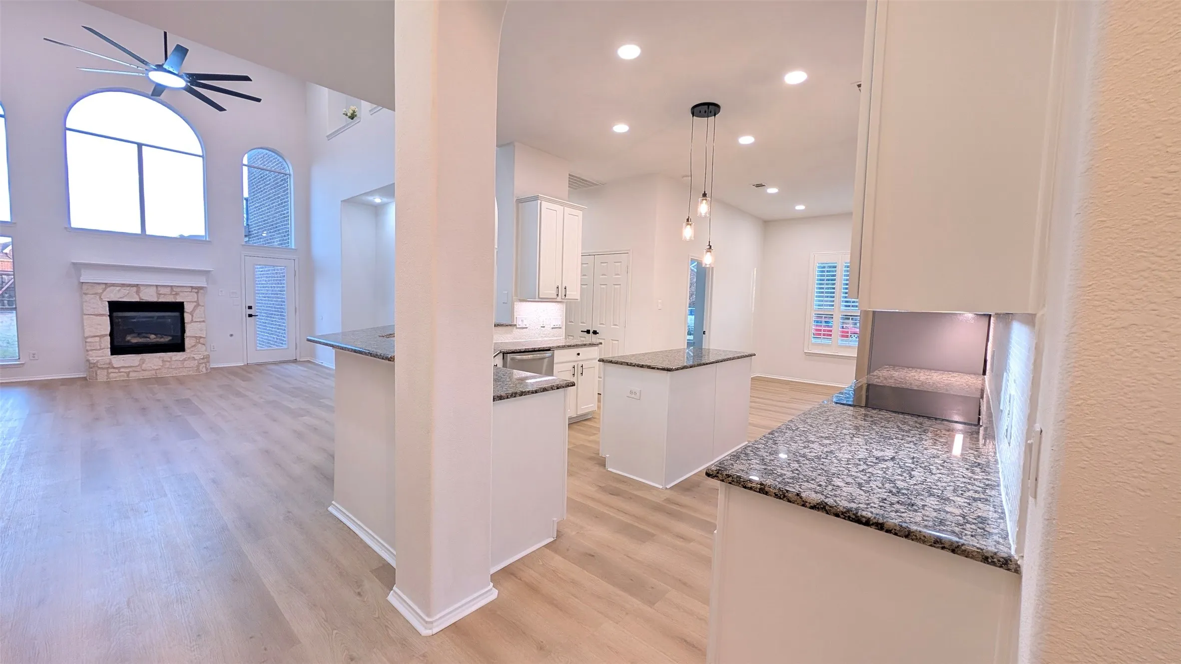 Kitchen with a center island, dark stone counters, hanging light fixtures, white cabinets, and light wood finished floors