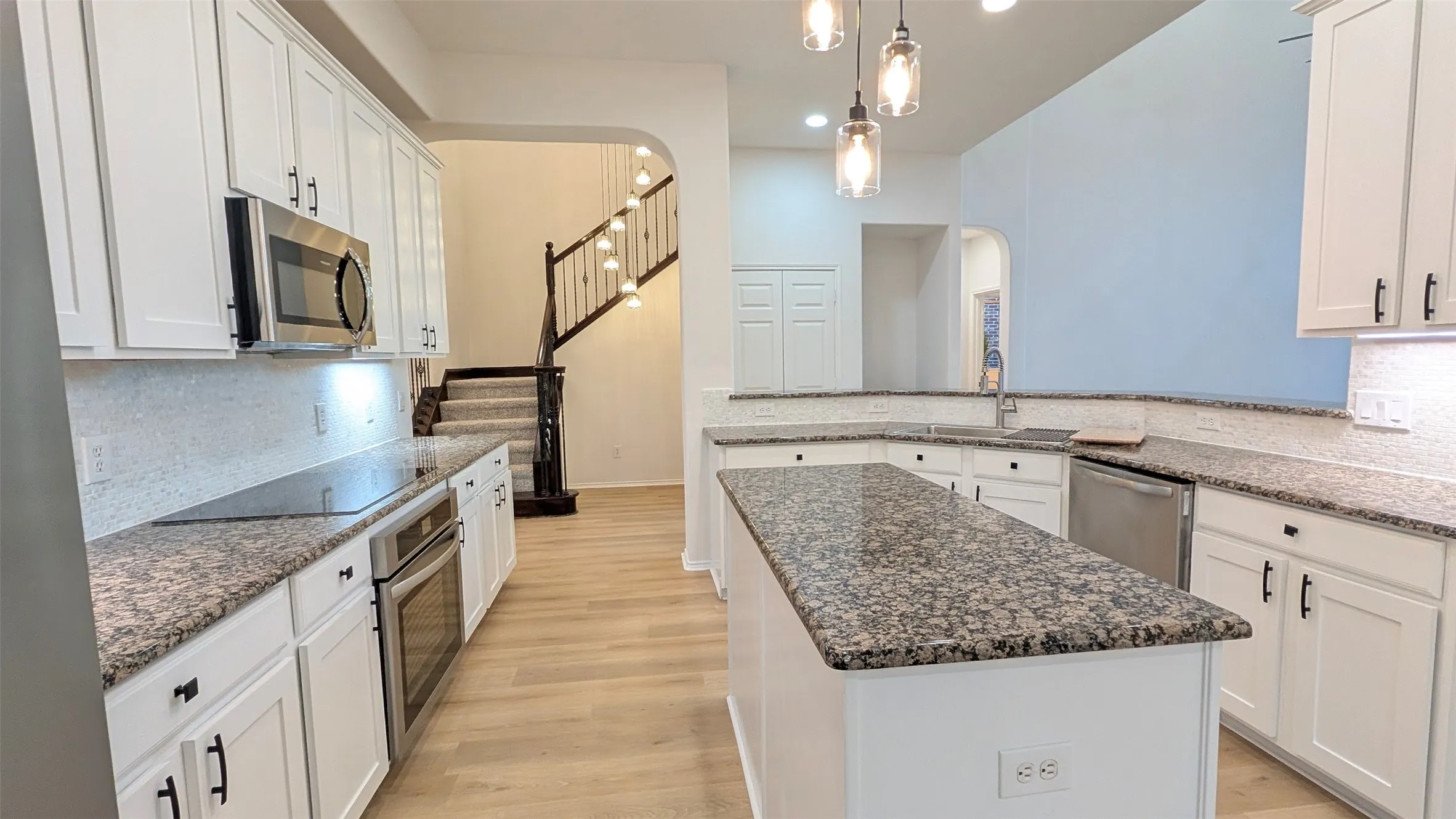 Kitchen featuring tasteful backsplash, light wood-style flooring, dark stone counters, and pendant lighting