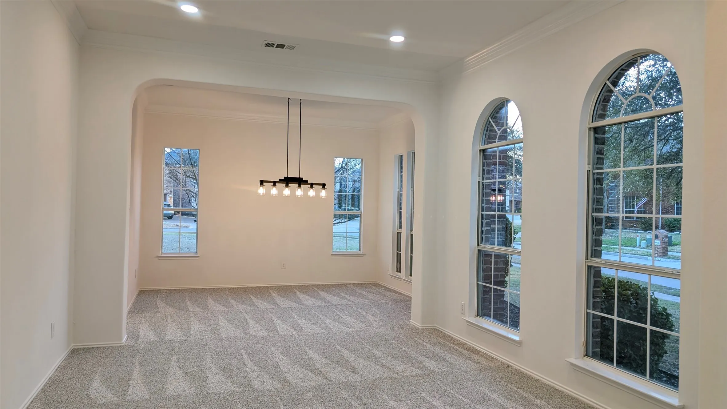 Unfurnished room with light colored carpet, ornamental molding, and arched walkways