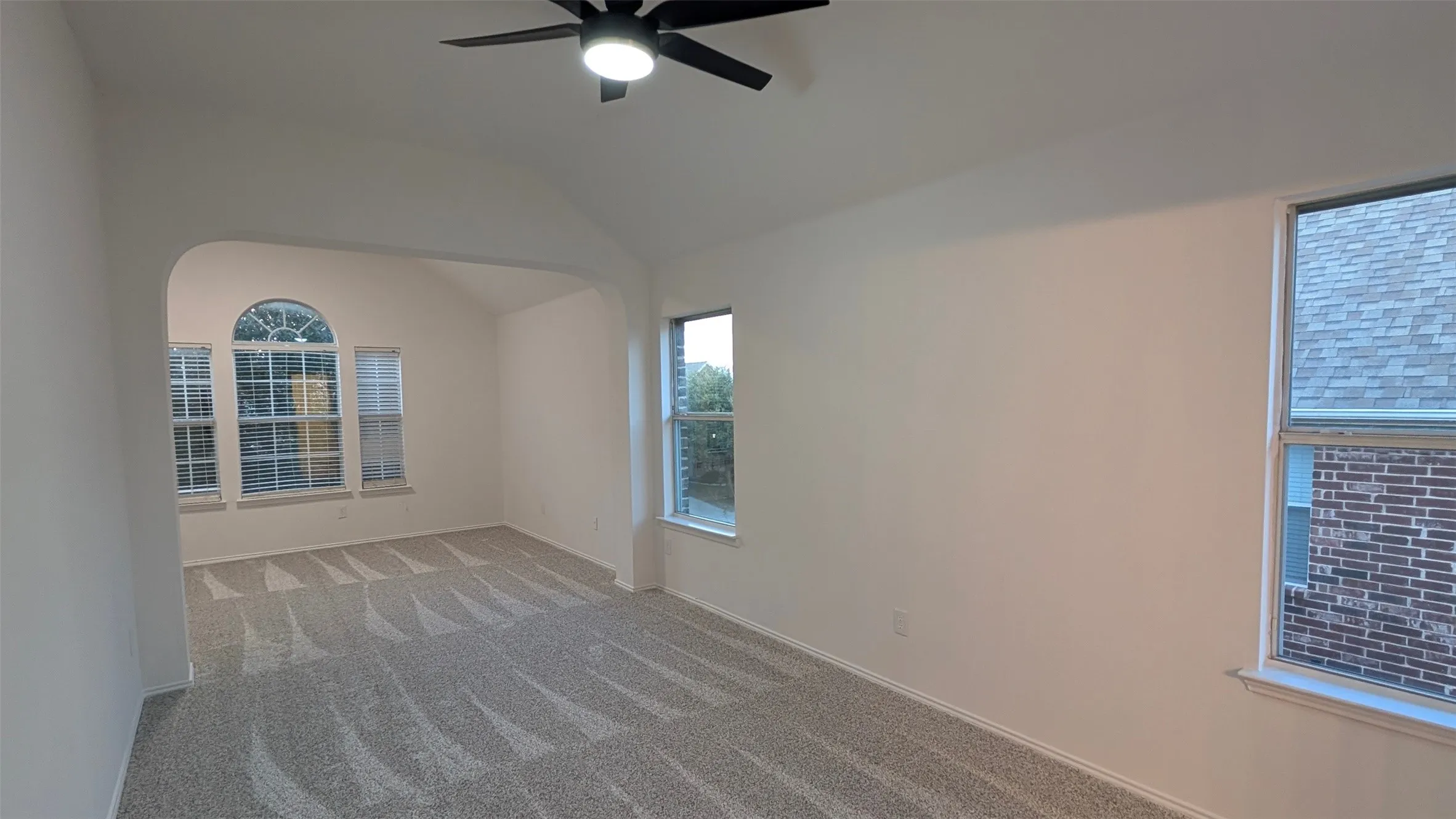 Carpeted empty room with vaulted ceiling and ceiling fan