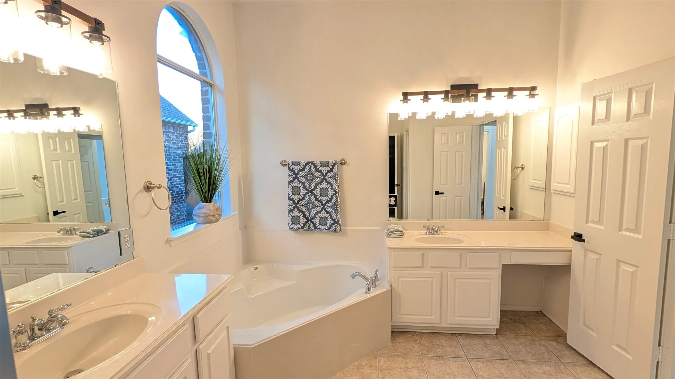 Full bathroom with two vanities, a garden tub, and light tile patterned floors