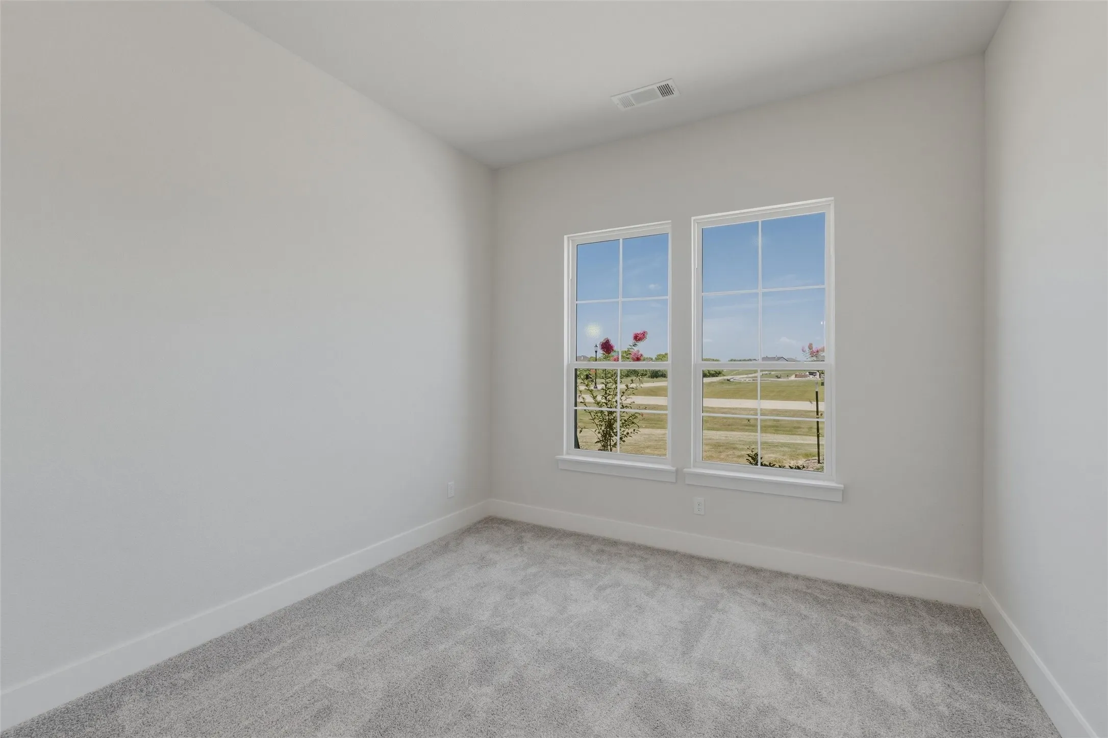Room featuring two large windows with white trim, light gray wall paint, gray carpet, and white baseboards