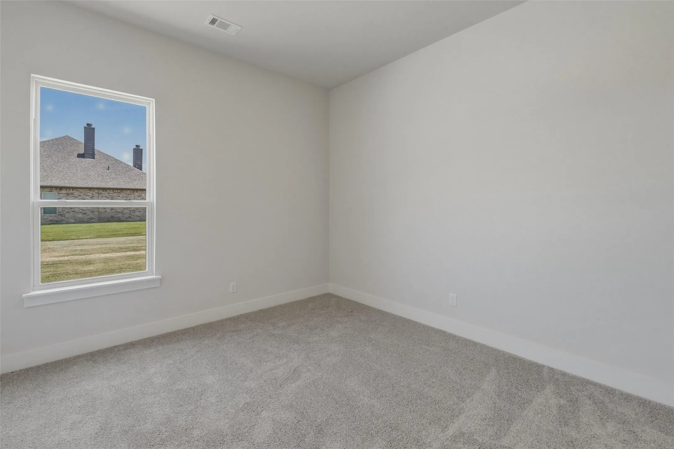 Carpeted interior room featuring a single window, light gray wall paint, and white trim