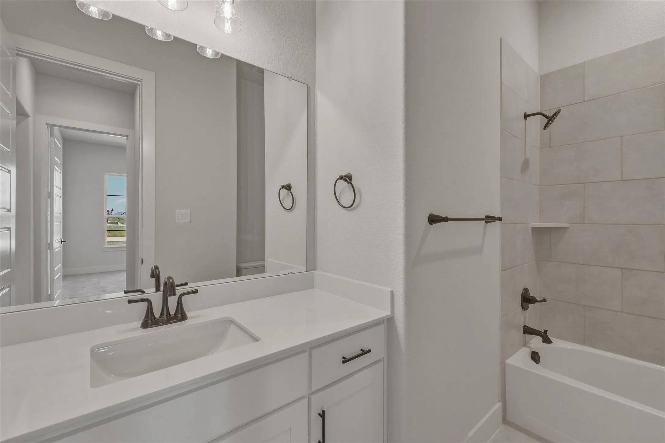 Bathroom featuring a single vanity with an undermount sink, a white countertop, and dark-finish hardware