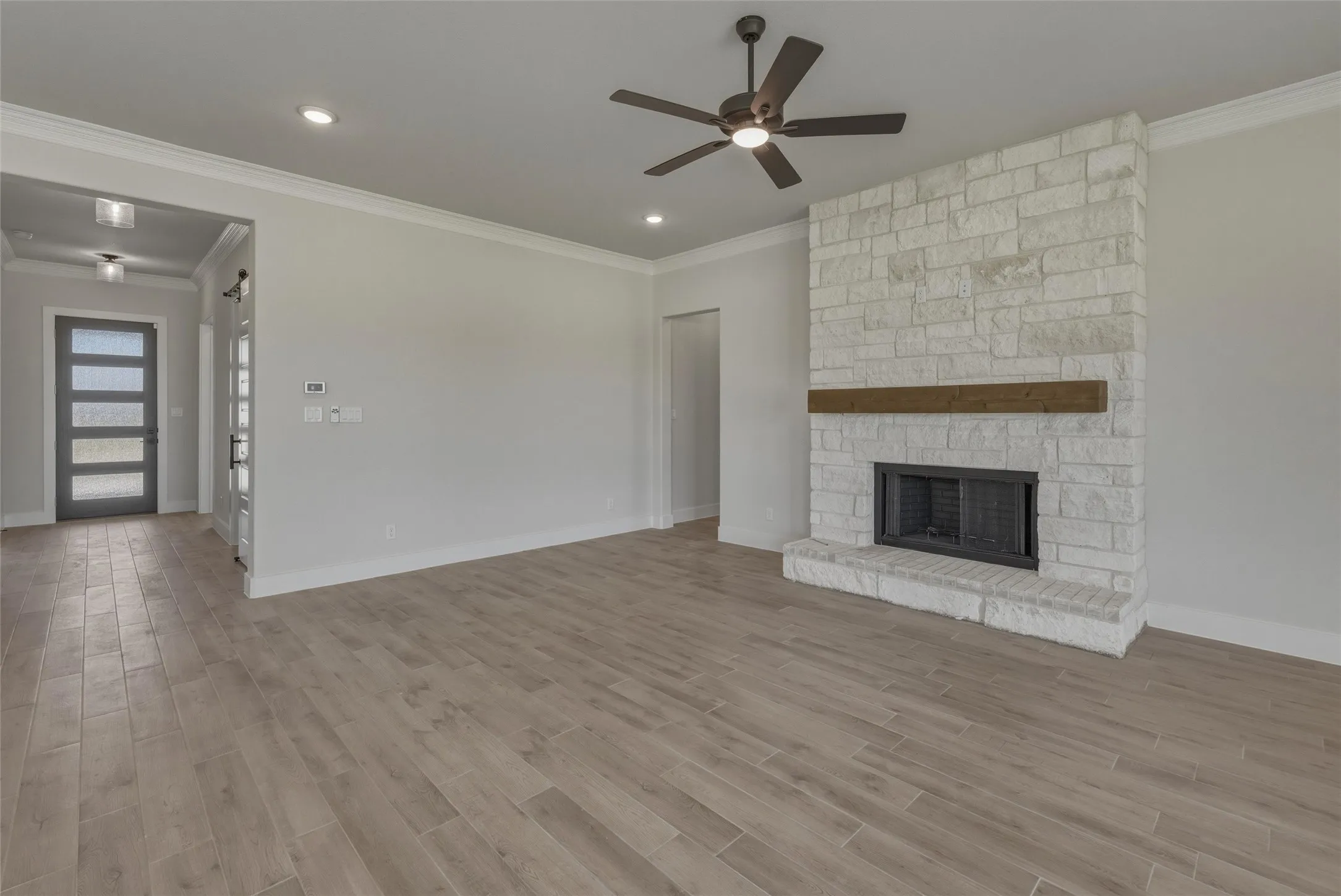 Living area featuring a stone fireplace with a wood mantel, a ceiling fan, recessed lighting, and wood-finish flooring