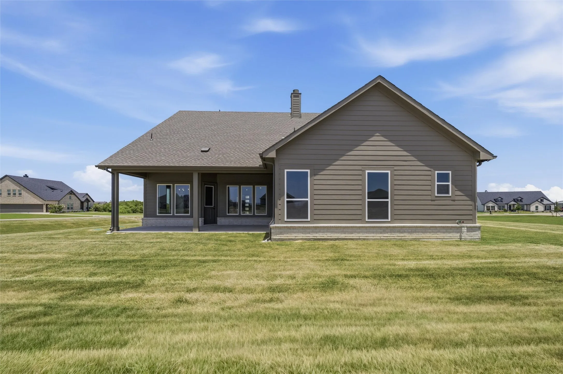 Rear exterior featuring a covered patio, multiple windows, siding facade, and a shingled roof
