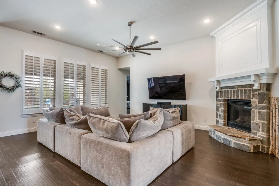 Living area with ceiling fan, dark wood-type flooring, a fireplace, and recessed lighting