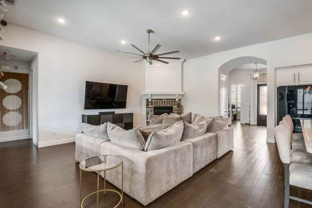 Living area with arched walkways, dark wood-style flooring, a ceiling fan, a fireplace, and recessed lighting