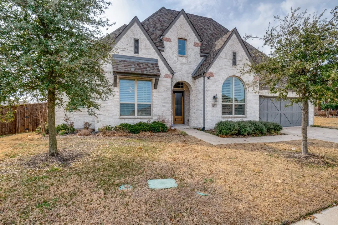 French provincial home with brick siding, a garage, concrete driveway, and roof with shingles