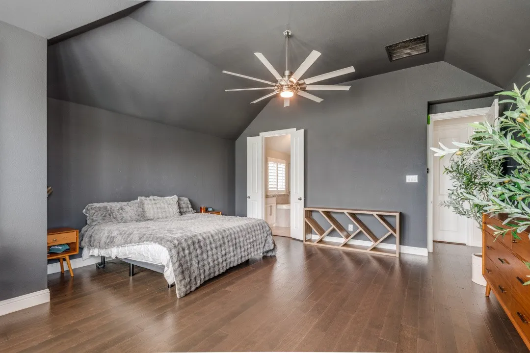 Bedroom featuring lofted ceiling, a ceiling fan, dark wood-type flooring, and ensuite bath