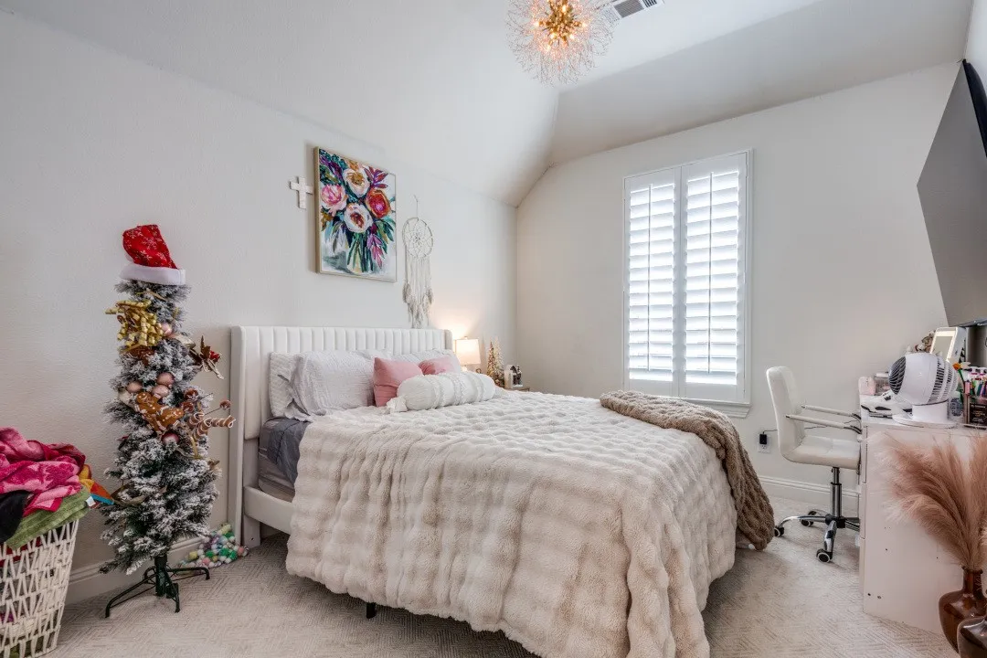 Carpeted bedroom featuring lofted ceiling and an office area