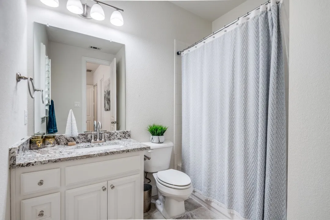 Bathroom featuring a shower with shower curtain, vanity, and a textured wall