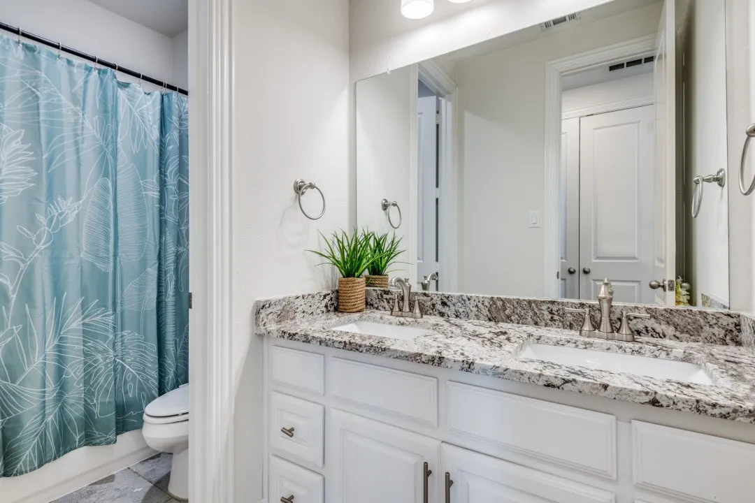Full bath with double vanity and shower / bath combination with curtain