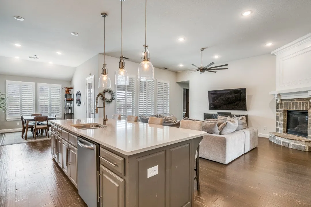 Kitchen with pendant lighting, a kitchen breakfast bar, light stone counters, a center island with sink, and a fireplace