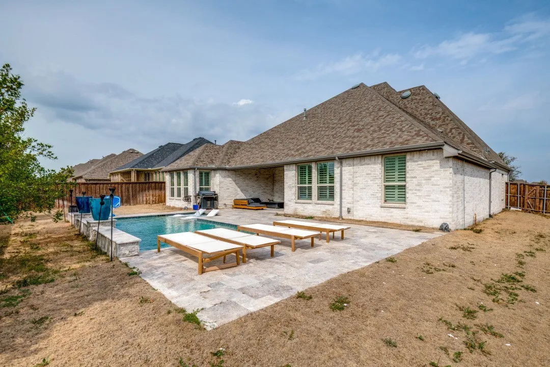 Rear view of property with brick siding, a patio area, a fenced backyard, and a shingled roof