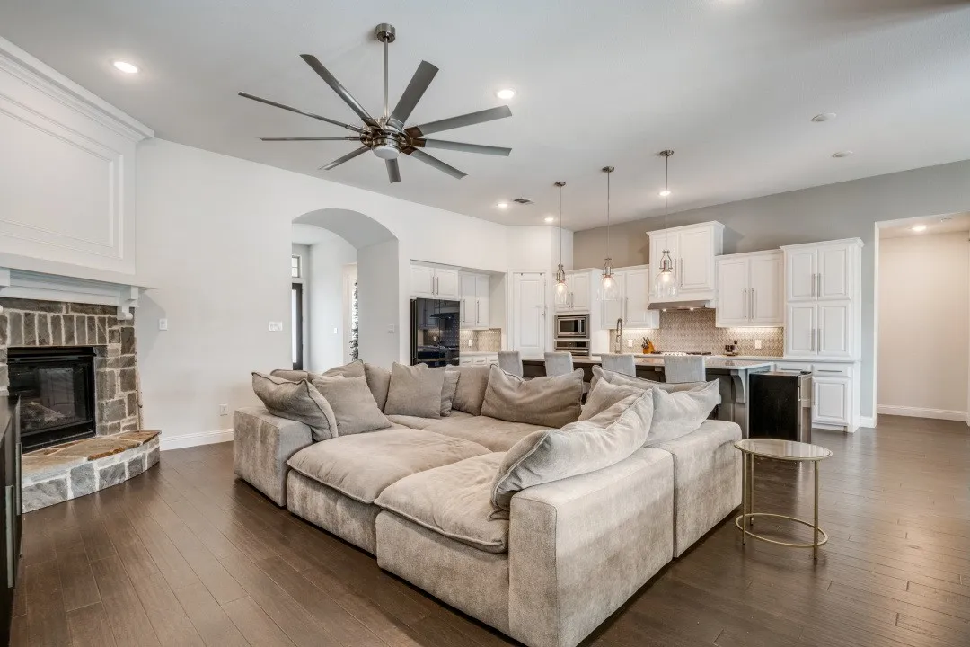 Living room featuring a fireplace, ceiling fan, arched walkways, dark wood-style flooring, and recessed lighting