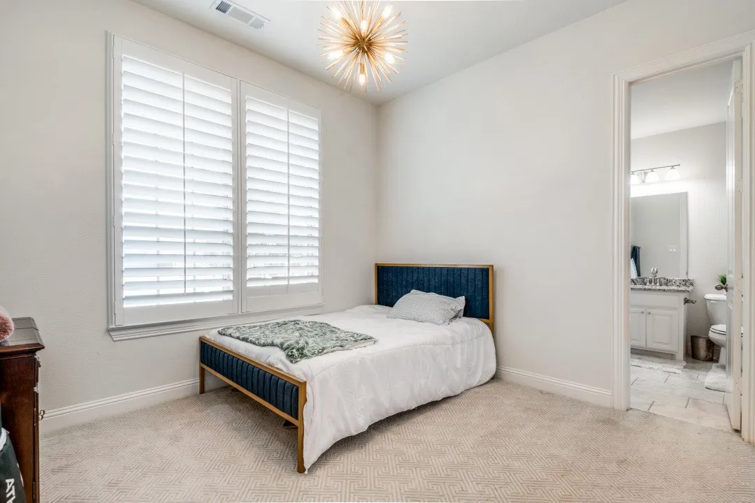 Bedroom with light colored carpet, ensuite bath, and hanging lights