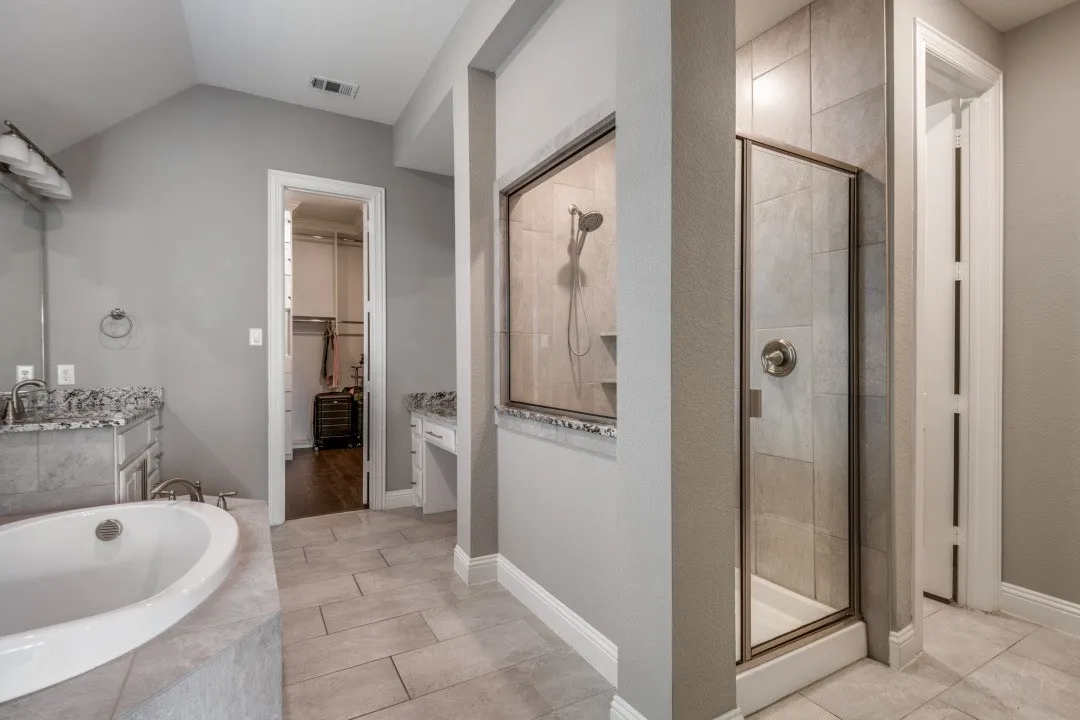 Bathroom featuring a walk in closet, vanity, a stall shower, a garden tub, and light tile patterned floors