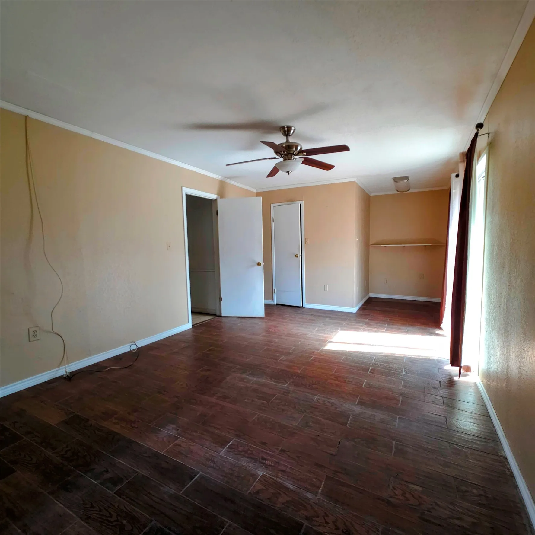 Spare room featuring crown molding, dark wood finished floors, and a ceiling fan