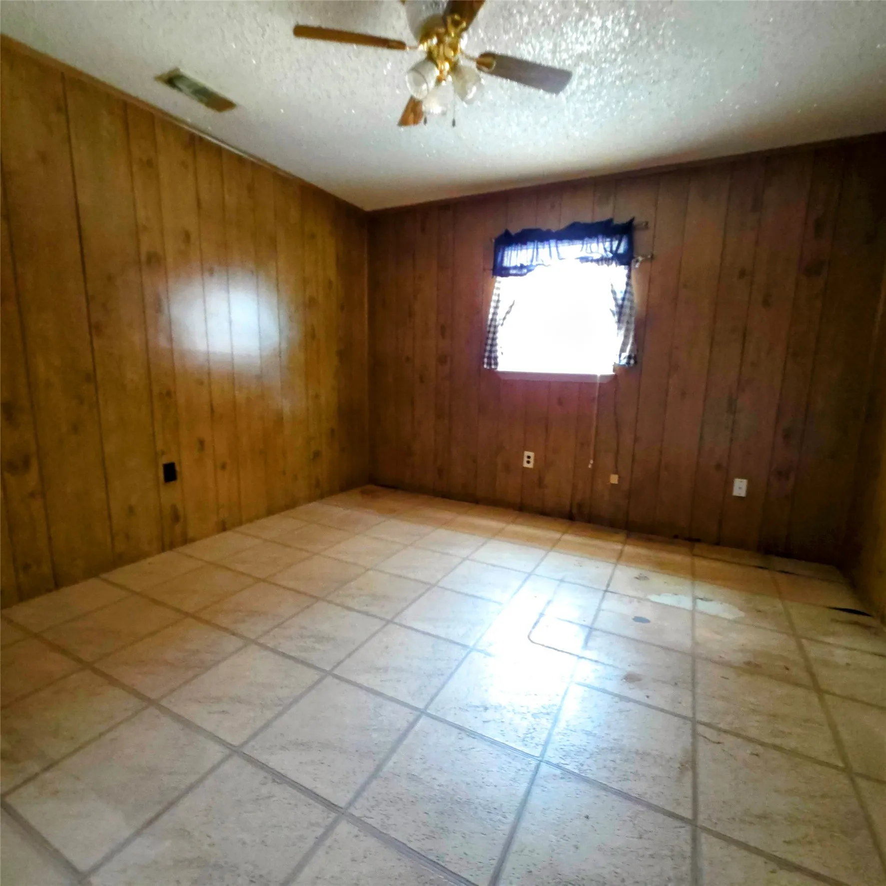 Unfurnished room featuring a ceiling fan and wooden walls
