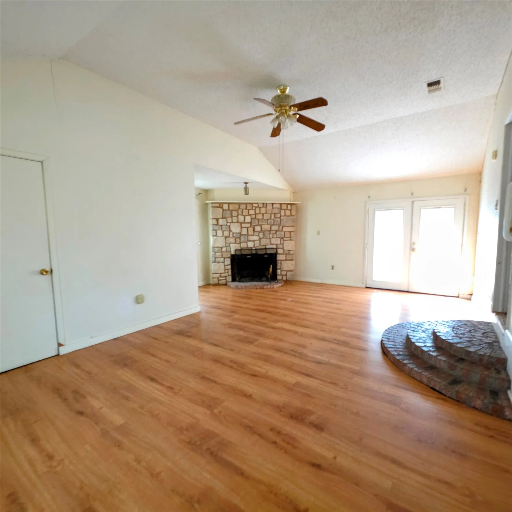 Unfurnished living room with ceiling fan, light wood-style floors, and a fireplace
