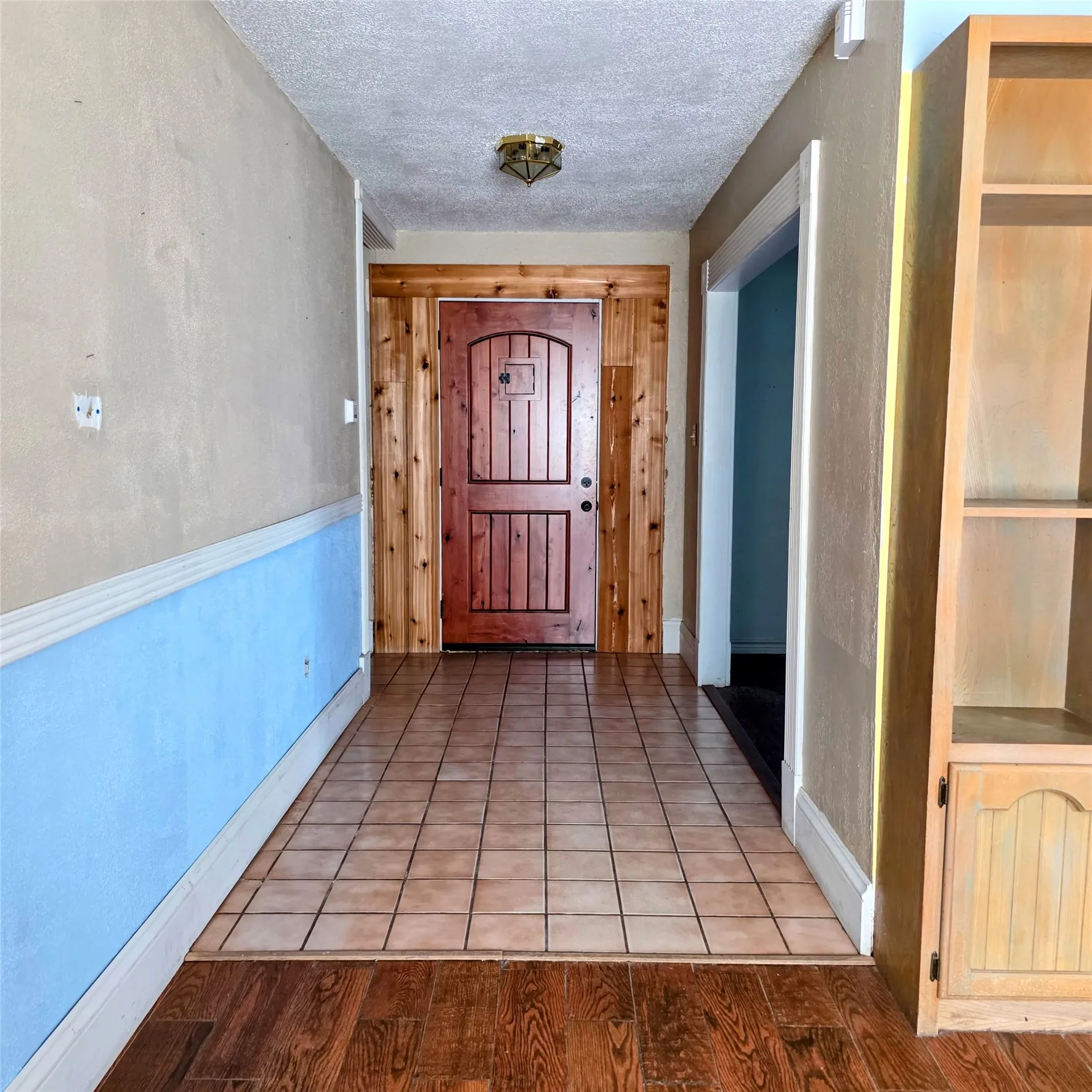 Foyer entrance with a textured ceiling and wood finished floors