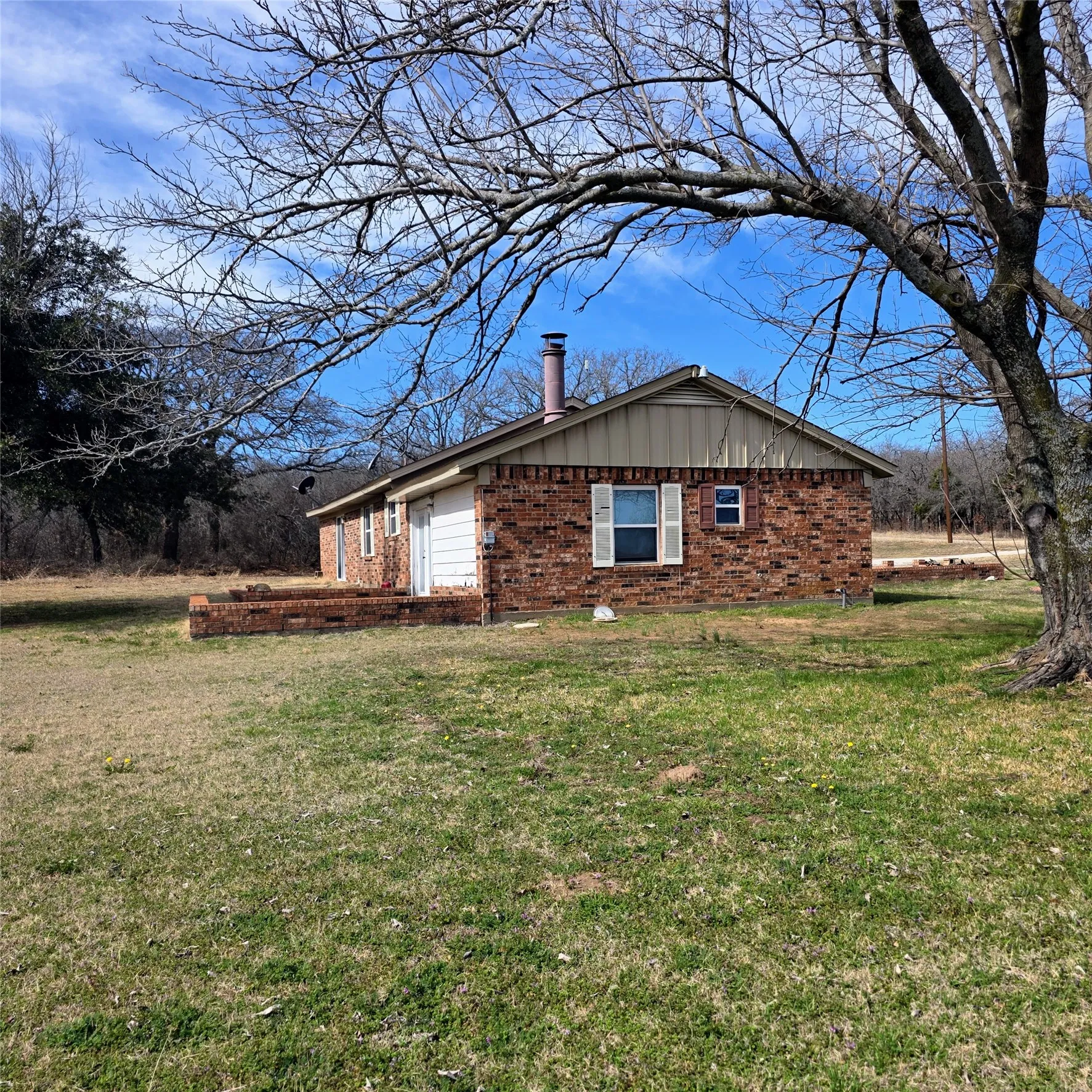 View of side of home with brick siding, a yard, and board and batten siding