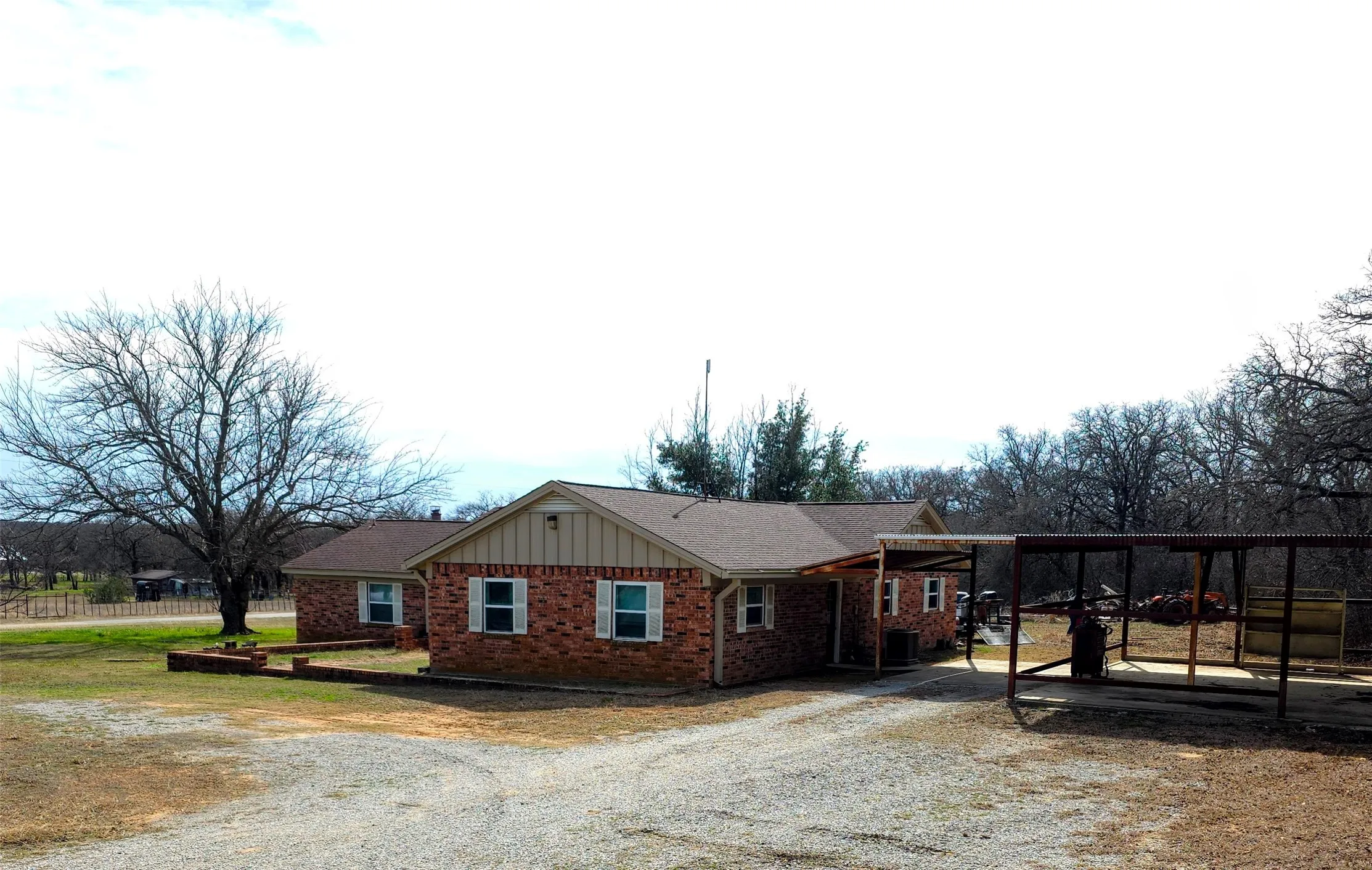 View of front of house featuring brick siding, driveway, board and batten siding, and a carport